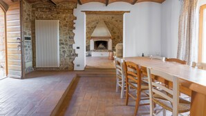 A rustic dining area with a stone wall, wooden ceiling beams, and a fireplace. - Le Fonti Apartments With Ac Near Siena (Poggibonsi)