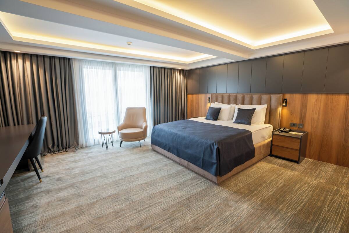 Moderni hotellihuone, jossa on suuri sänky, työpöytä, tuoli ja pieni pöytä.
