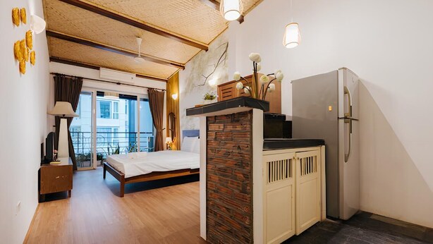 A compact bedroom with a bed, a small desk, and a kitchenette. - Ha Noi Memory Apartel (Hanoi)