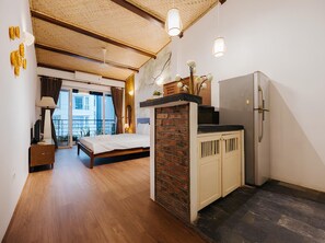 Un dormitorio pequeño con cama, un escritorio y kitchenette.