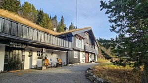 A traditional wooden building with a thatched roof, a gravel driveway, and a bench outside. - 4 bedroom beautiful home in Hemsedal (Hemsedal)