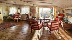 A spacious living room with wooden flooring, a dining area with a round table, and a view through large windows. - 4 bedroom beautiful home in Hemsedal (Hemsedal)