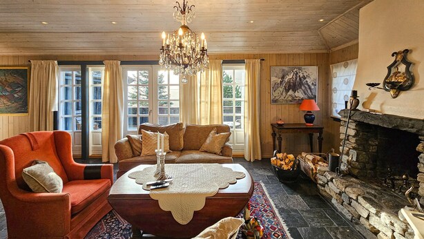A cozy living room with a fireplace, a chandelier, and a sofa with cushions. - 4 bedroom beautiful home in Hemsedal (Hemsedal)