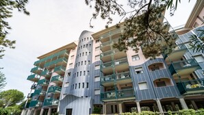 A multi-story hotel with balconies, a central atrium, and a well-maintained lawn. - Spacious stay in a beautiful residence (Bibione)