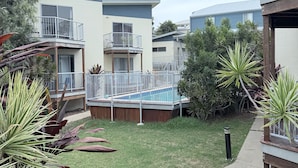 A residential building with a swimming pool, surrounded by various plants and a well-maintained lawn. - Emu Park Beach Resort (Emu Park)