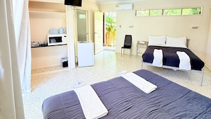 A hotel room with two beds, a ceiling fan, a TV mounted on the wall, and a kitchenette area. - Emu Park Beach Resort (Emu Park)