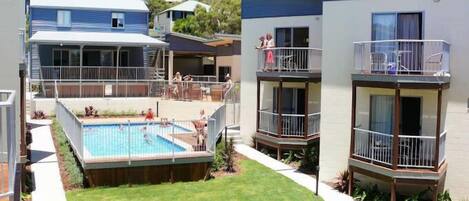 Un complejo residencial con piscina, varios balcones y un césped bien cuidado.