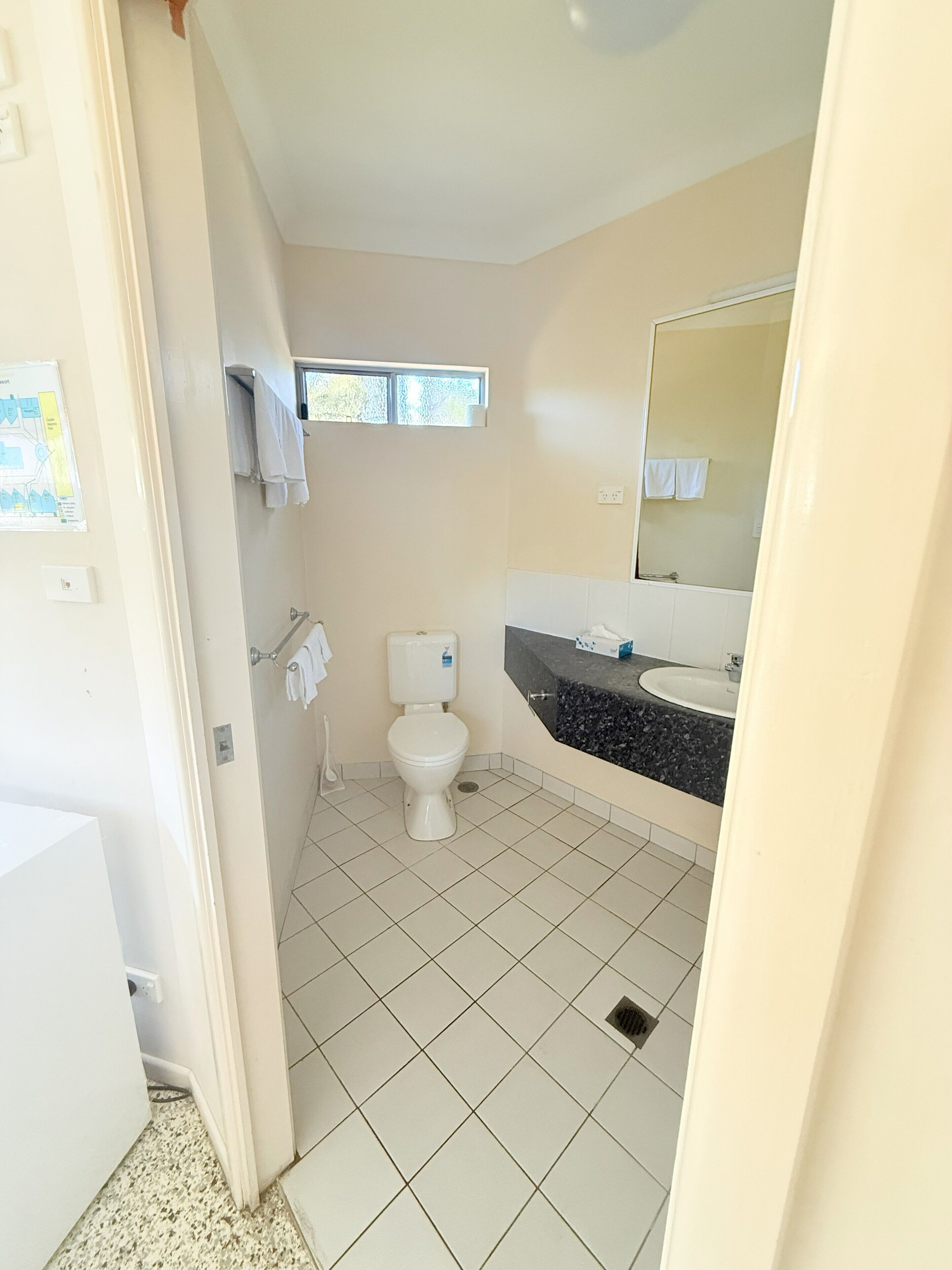 A bathroom with a toilet, sink, and mirror.