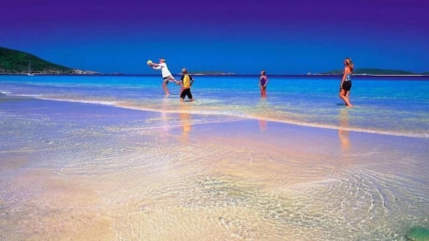 A beach scene with clear water and a person playing with a ball. - Emu Park Beach Resort (Emu Park)