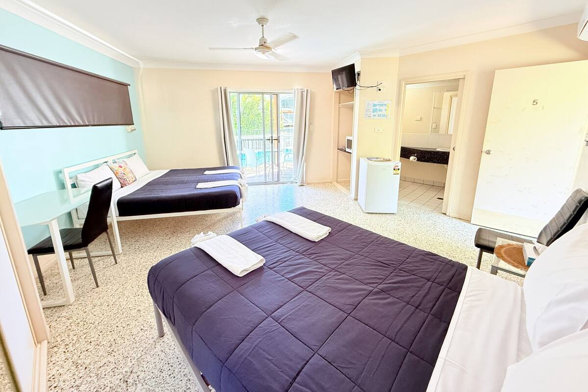 Ein Hotelzimmer mit Bett, Schreibtisch, Stuhl, Fernseher und Badezimmer.