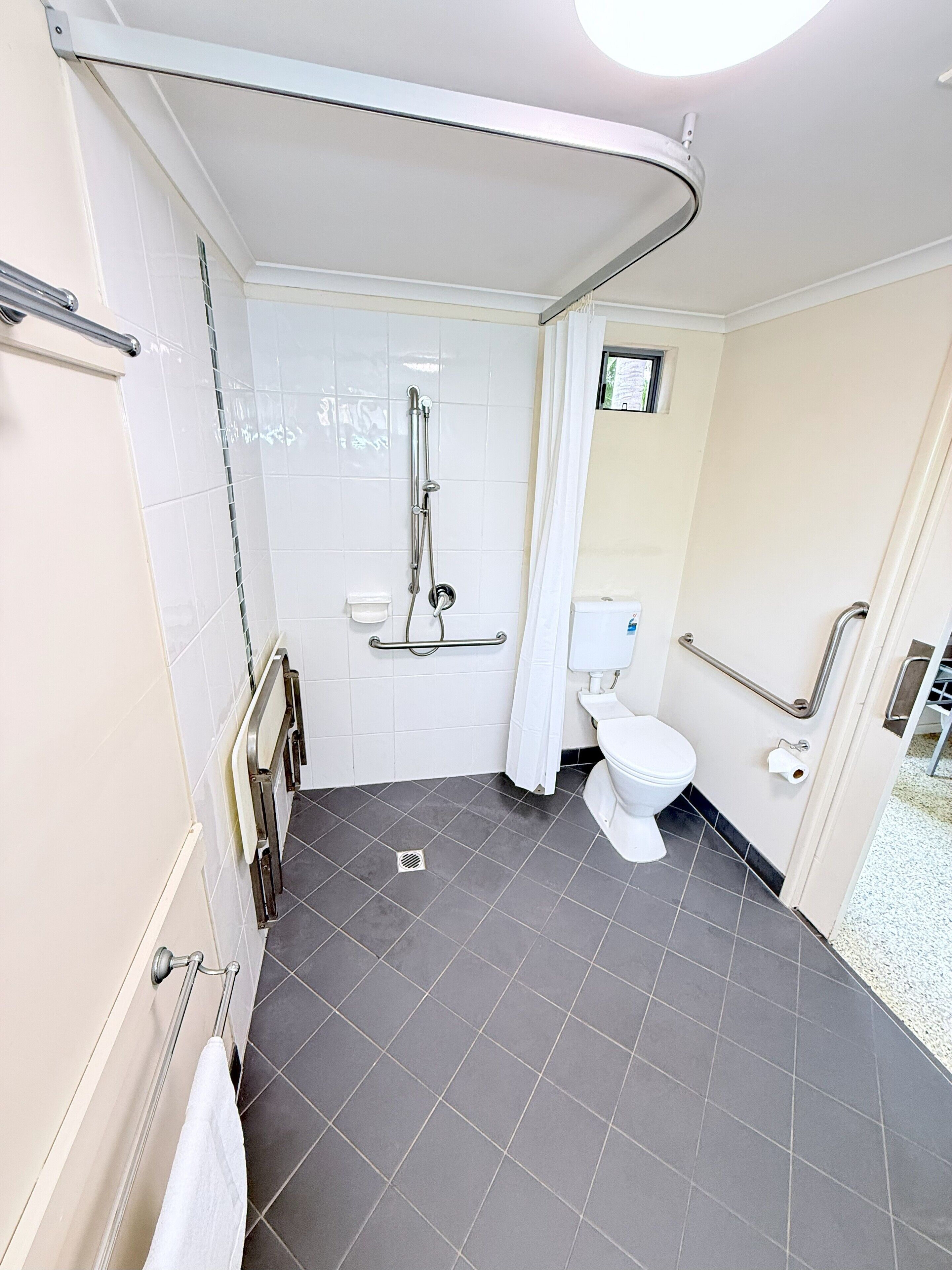 Une salle de bain moderne équipée d’une douche, de toilettes et de barres d’appui.