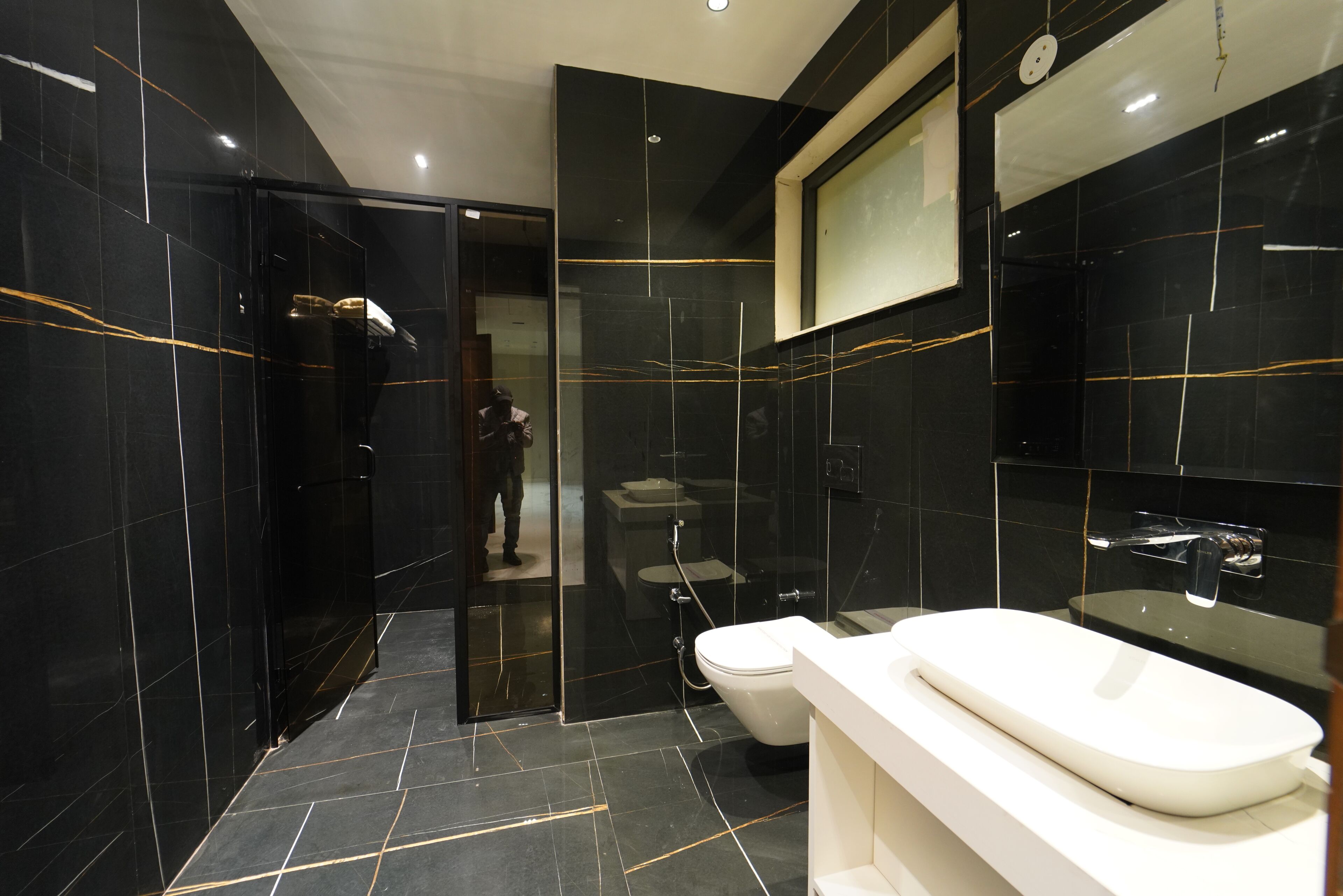 A modern bathroom with a large mirror, a white sink, and a glass-enclosed shower area.
