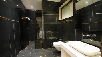 A modern bathroom with a large mirror, a white sink, and a glass-enclosed shower area.