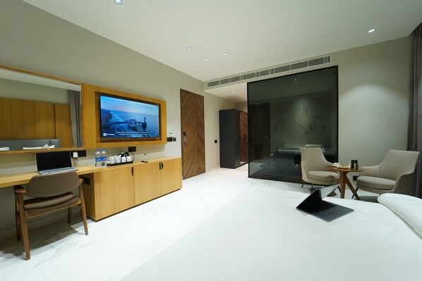 A modern hotel room with a wooden desk, a laptop, a flat-screen TV, a sofa, and two armchairs. - Hotel Millennium (Hisar)
