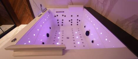 Una bañera de hidromasaje moderna con múltiples chorros, un panel de control e iluminación LED.
