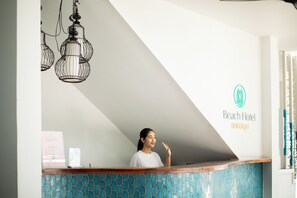 Un comptoir d’accueil avec un mur recouvert de carreaux et le logo de l’hôtel Beach Hotel Dhigurah.