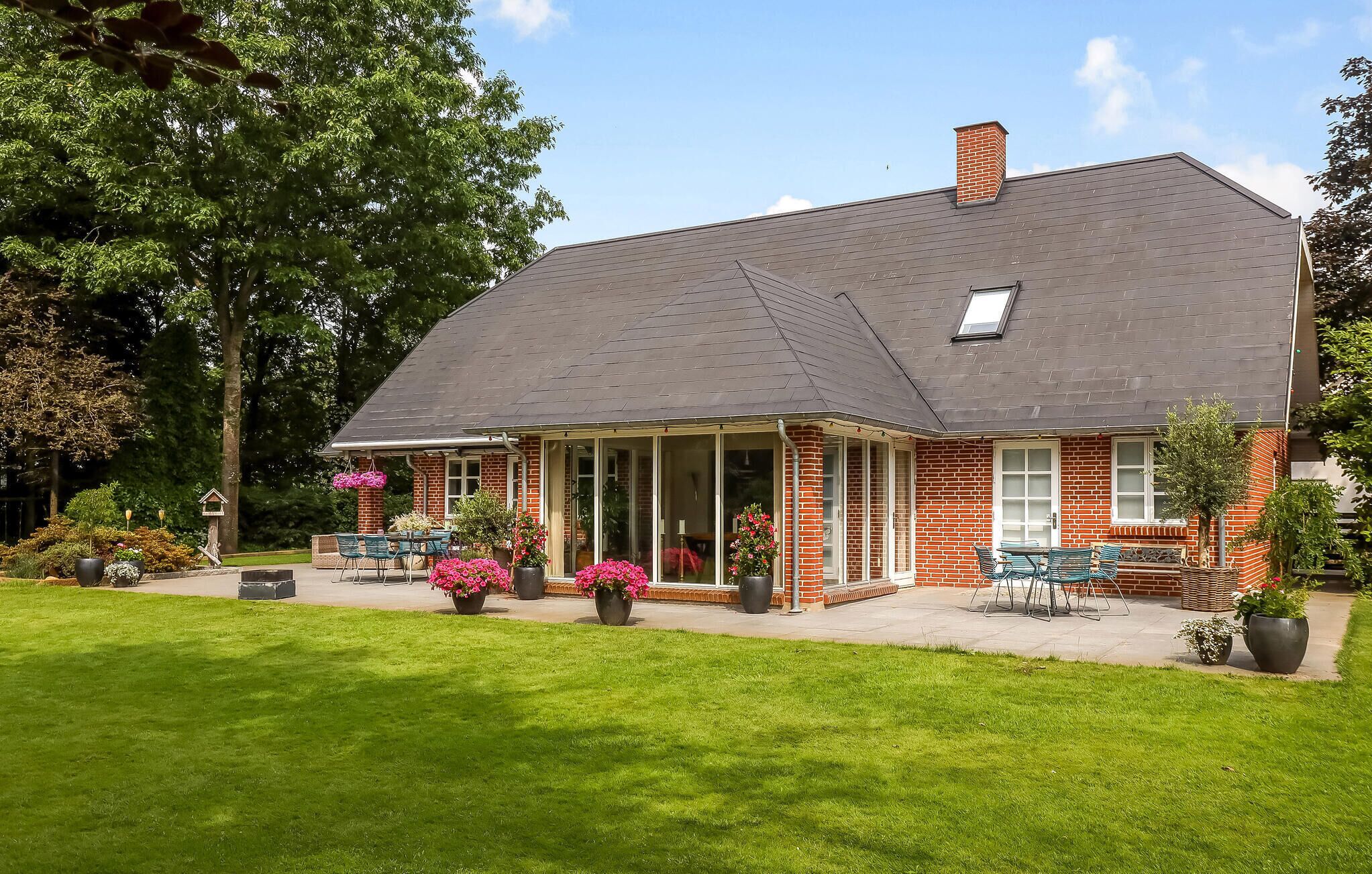 Ein zweistöckiges Haus mit einer Veranda, Ziegel Fassade und einem gepflegten Rasen.