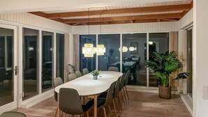 A dining area with a large table, chairs, and potted plants.