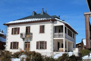 En toetagers bygning med balkon, dør og vindue med skodder.