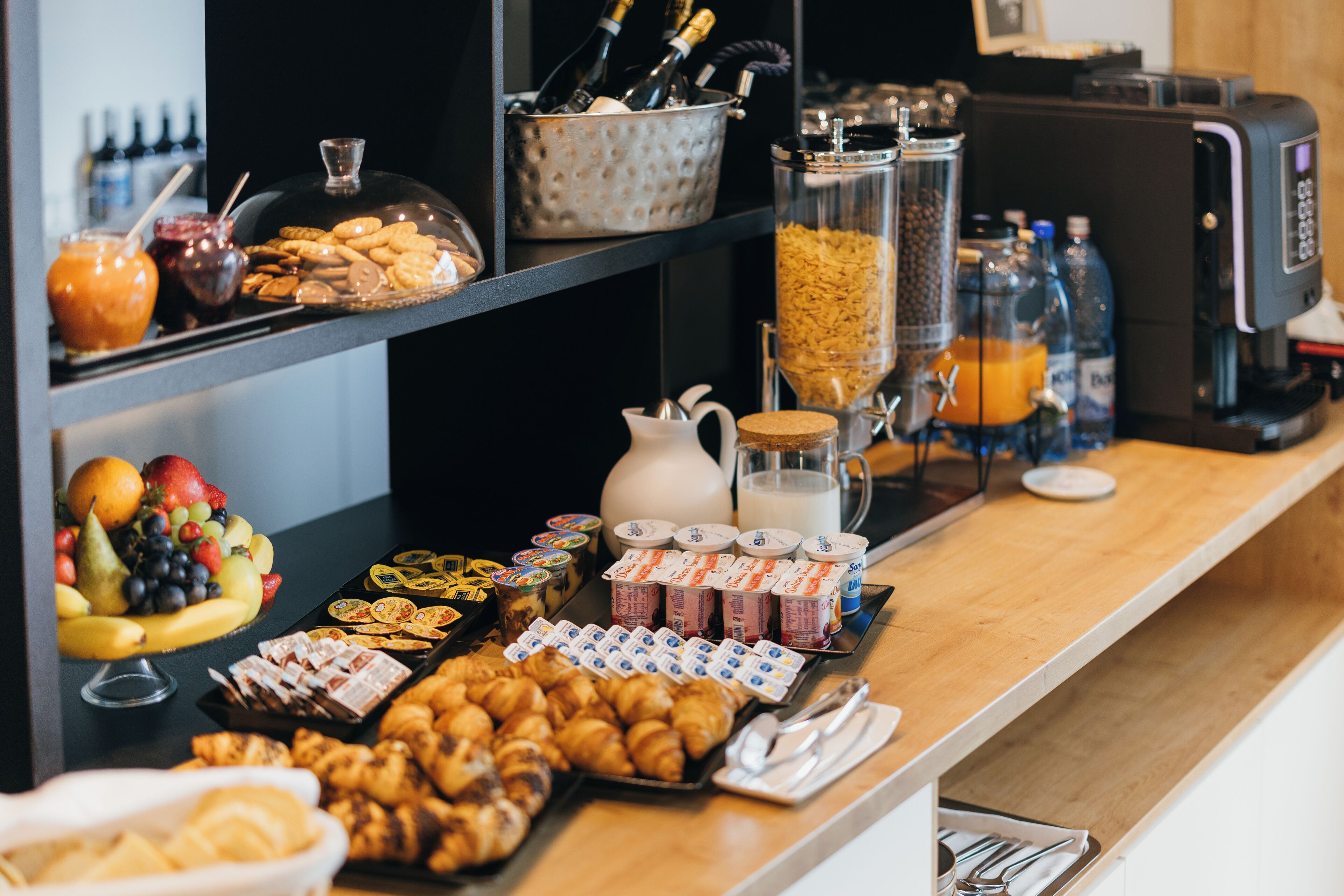 Un bufé de desayuno con diversos alimentos, bebidas y una máquina de café.