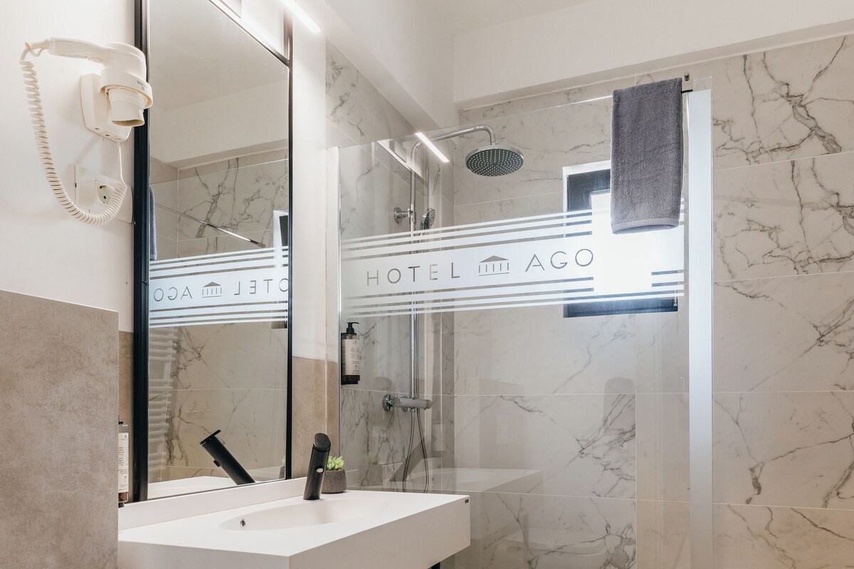 Un baño moderno con un lavamanos blanco, un espejo grande y una zona de ducha.