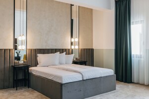Un dormitorio moderno con una cama grande, mesitas de noche, un espejo y lámparas colgantes.