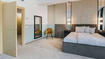 Une chambre d’hôtel moderne avec un grand lit, une chaise, une table de chevet et un miroir.