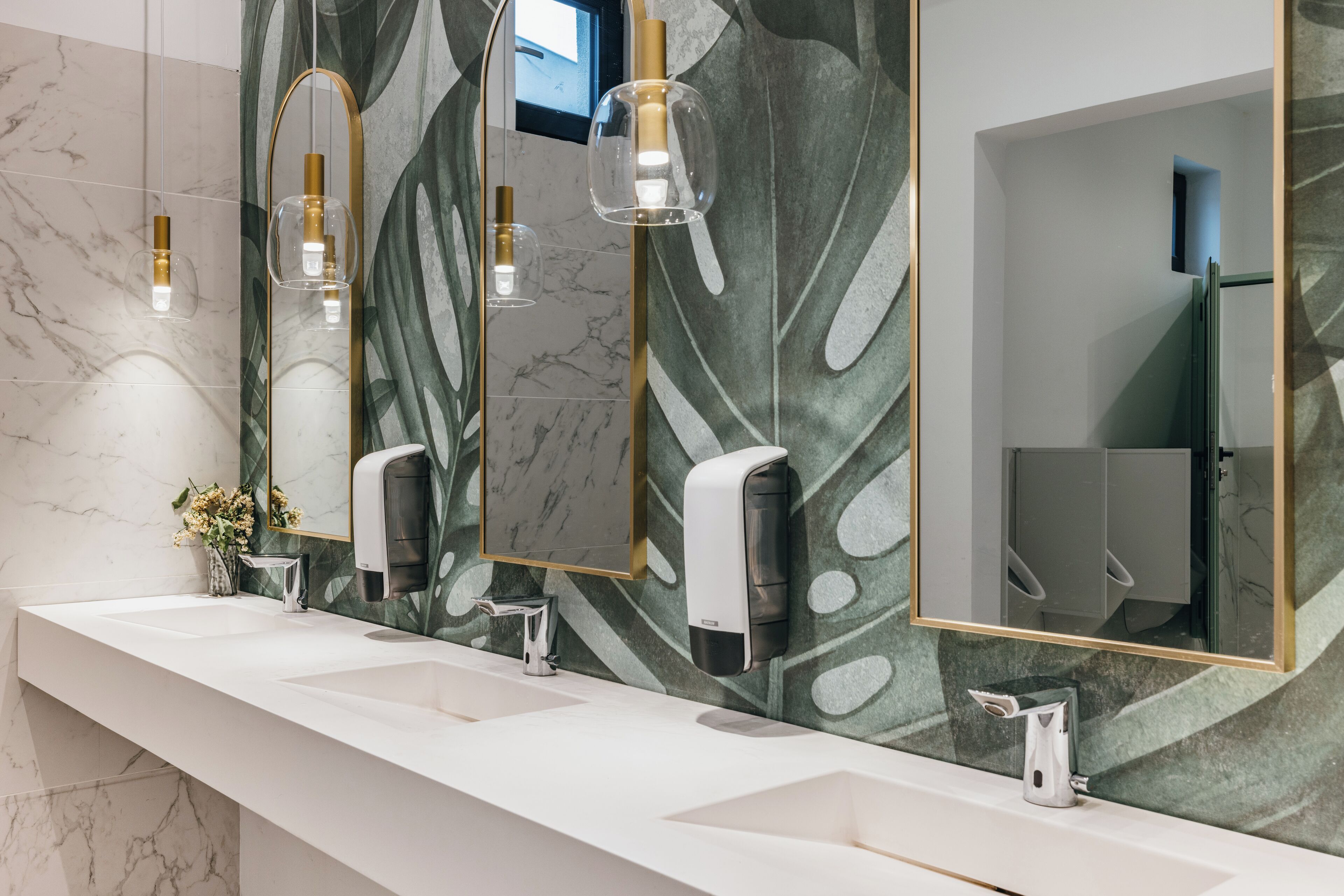 A modern bathroom with two sinks, a large mirror, and a soap dispenser.