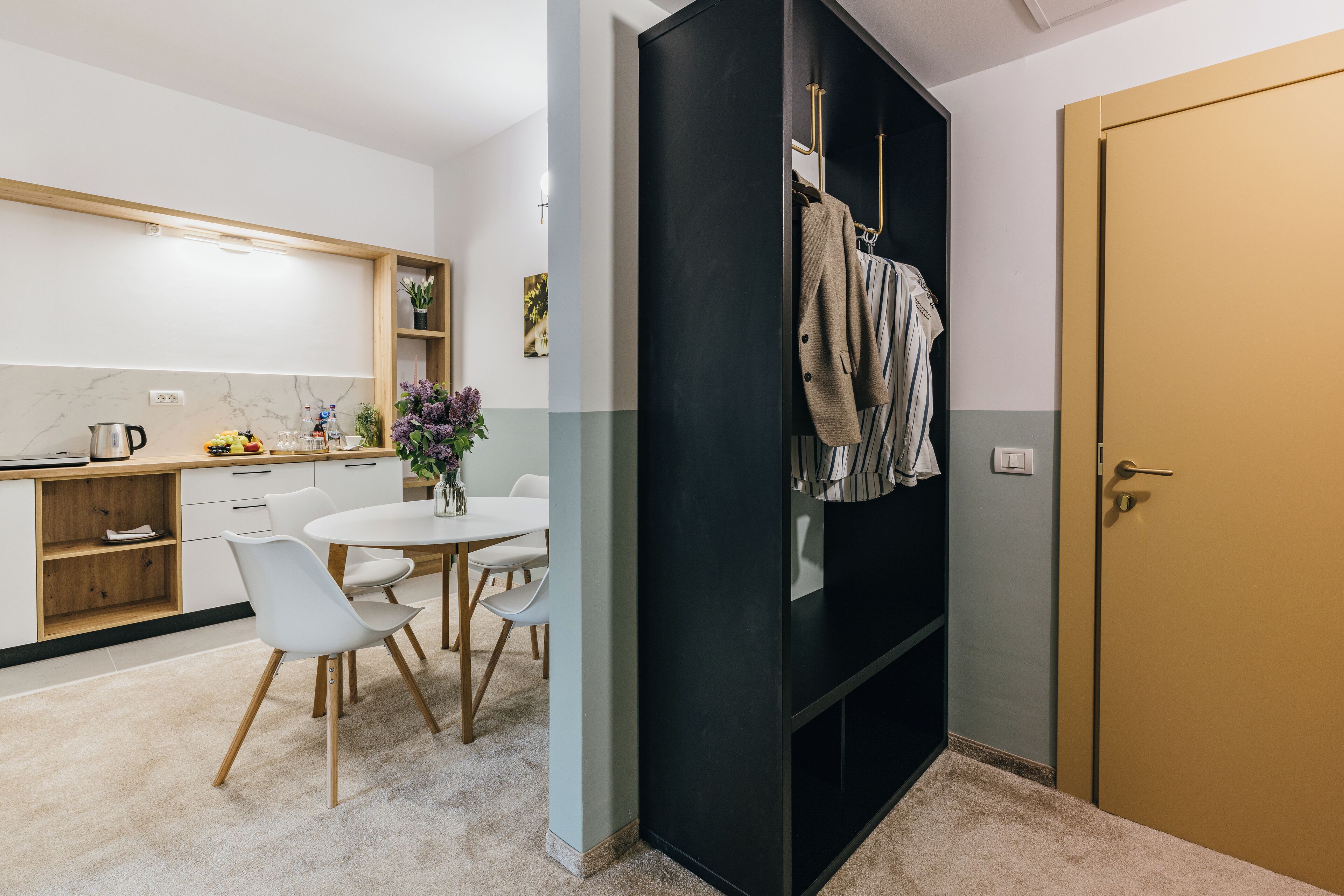 A modern kitchen with white cabinets, a marble backsplash, and a dining area with a white table and chairs.