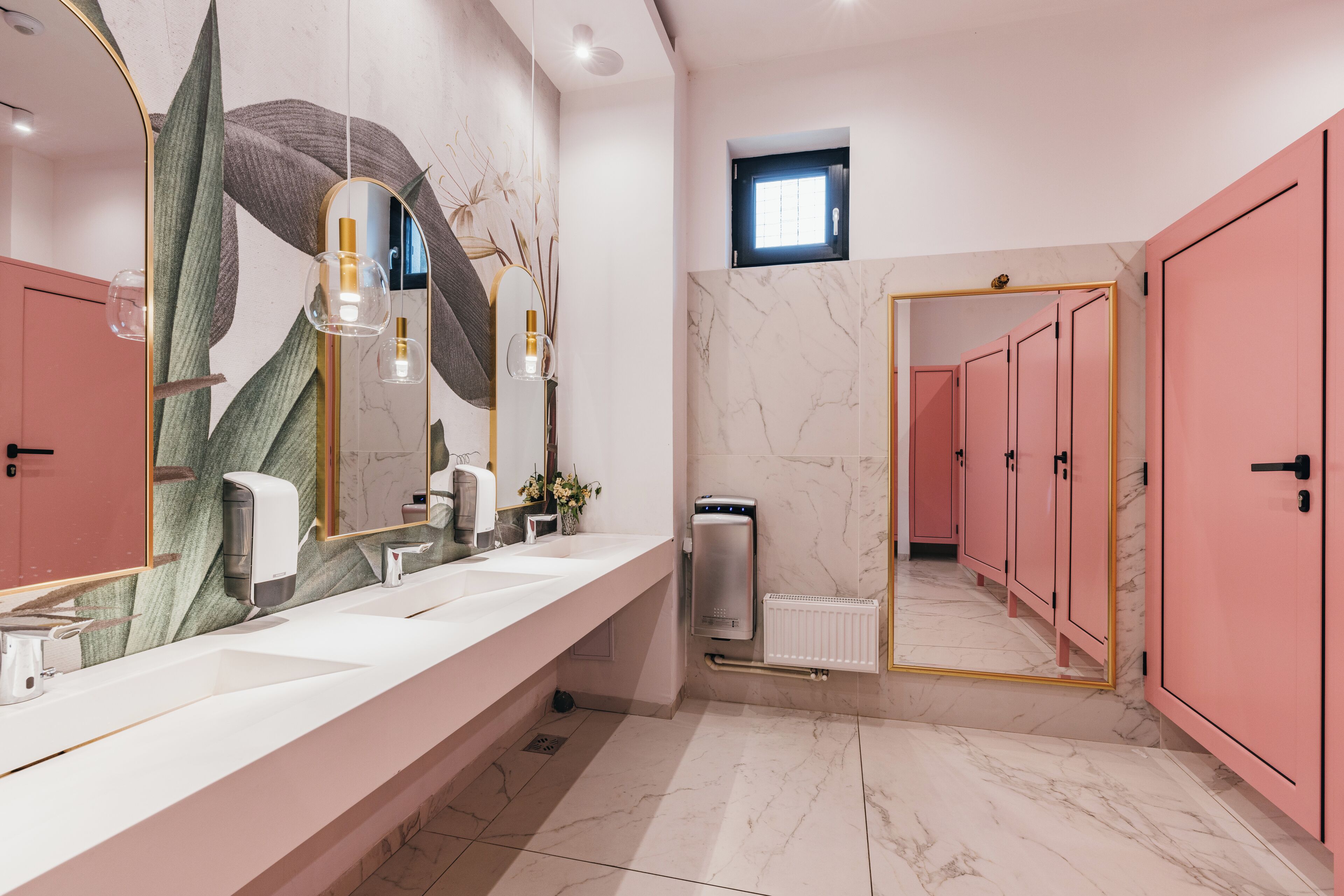 A modern bathroom with a long vanity, a large mirror, and pink cabinets.