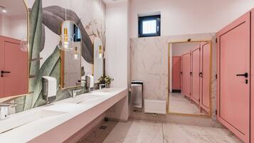 A modern bathroom with a long vanity, a large mirror, and pink cabinets.