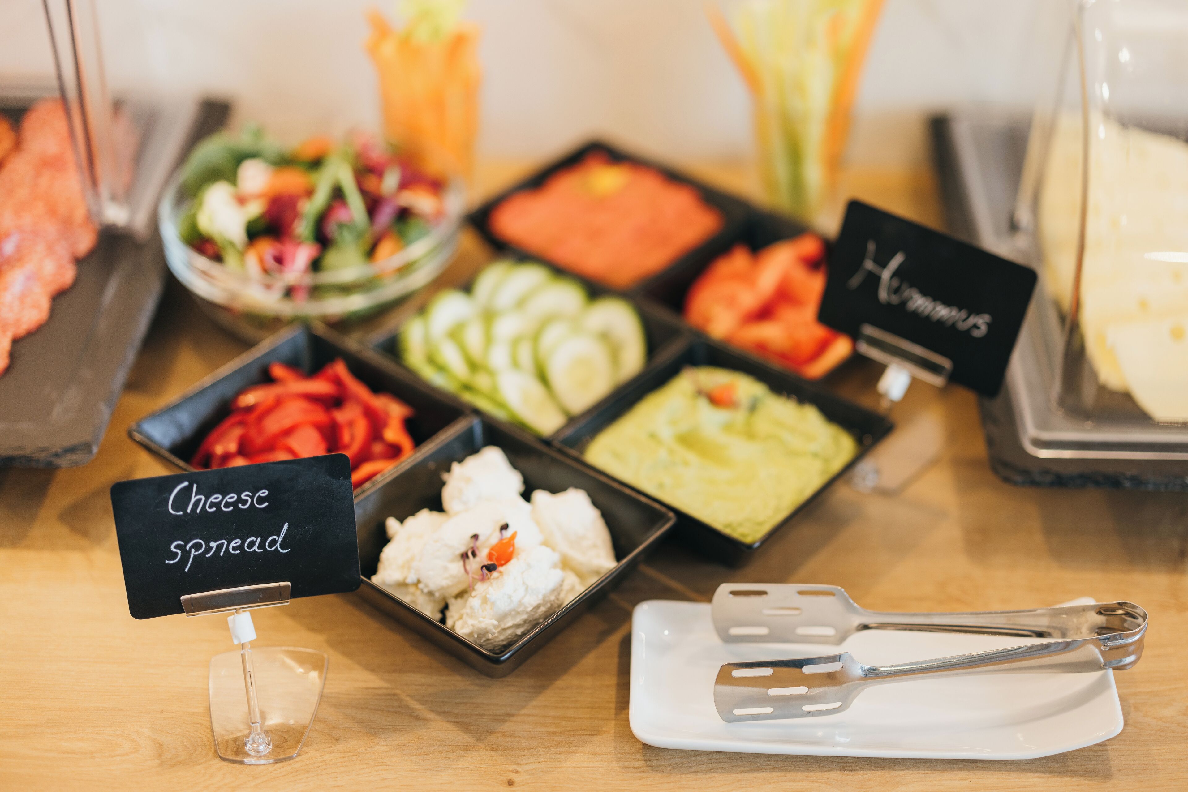 A buffet table with various food items including cheese spread, salads, and other dishes.