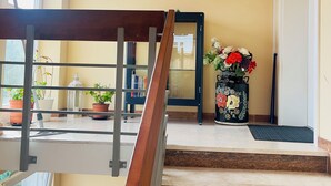 A staircase with a wooden handrail leading to a landing with a framed picture, potted plants, and a door. - Apartment Kelkheim (Kelkheim (Taunus))
