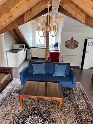 A loft-style living space with a blue sofa, wooden coffee table, and a patterned rug.