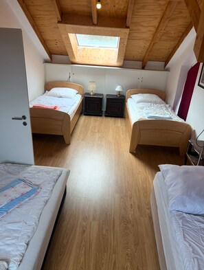 A compact room with two wooden beds, a skylight, and a small window.