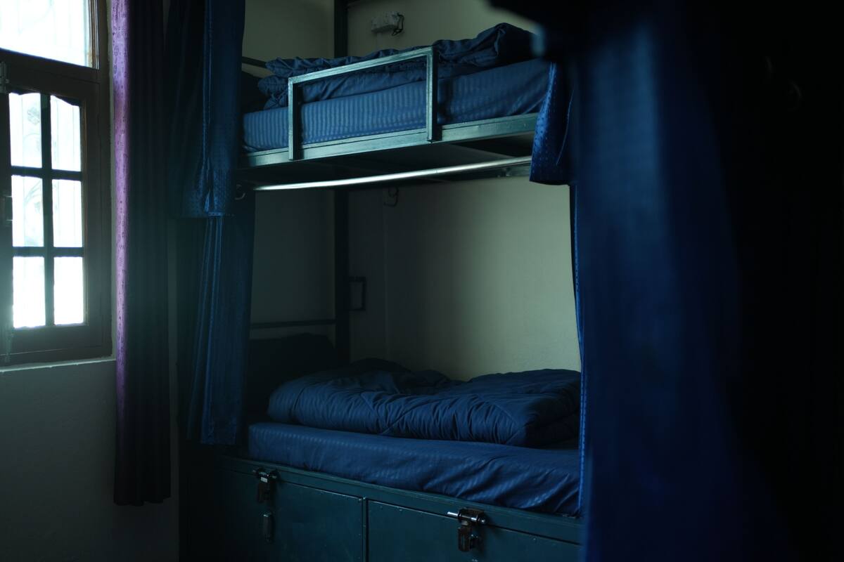 A bunk bed room with a window and curtains.