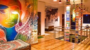 Un intérieur moderne agrémenté d’une fresque murale colorée, de planchers en bois et d’un escalier orné de drapeaux de différents pays.