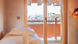 A bedroom with a bed, a window with a view of a snowy landscape, and a wooden door. - Beautiful apartment for 6 guests with WIFI, TV and terrace (Basse-nendaz)