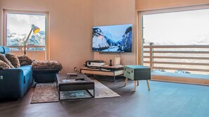 A modern living room with a large TV, comfortable seating, and a view of a snowy mountain. - Beautiful apartment for 6 guests with WIFI, TV and terrace (Basse-nendaz)
