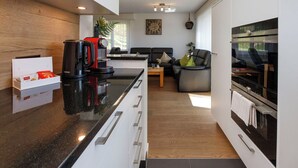 Cozinha moderna com bancada preta, cafeteira e forno Siemens.