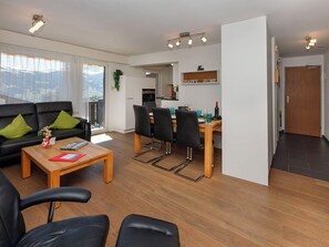 Ein modernes Wohnzimmer mit einer schwarzen Couch, einem Holztisch und einem Essbereich mit Stühlen und Tisch.