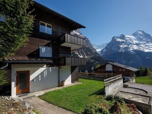 Een chalet met twee verdiepingen, een balkon, een houten terras en uitzicht op de bergen.