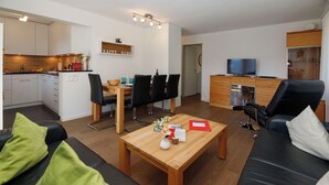 Uma sala de estar moderna com sofá, mesa de centro e área de jantar com cadeiras e mesa.