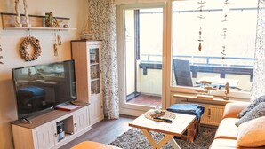 Un salon avec un téléviseur, un canapé et un balcon offrant une vue agréable.