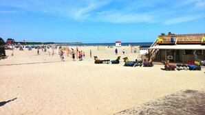 Une plage avec une structure en bois, des chaises de plage et des parasols.