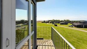 Een balkon met uitzicht op een camping met meerdere hutten en een weg.