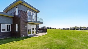 Een modern huis met twee verdiepingen, een balkon, grote ramen en een verzorgd gazon.