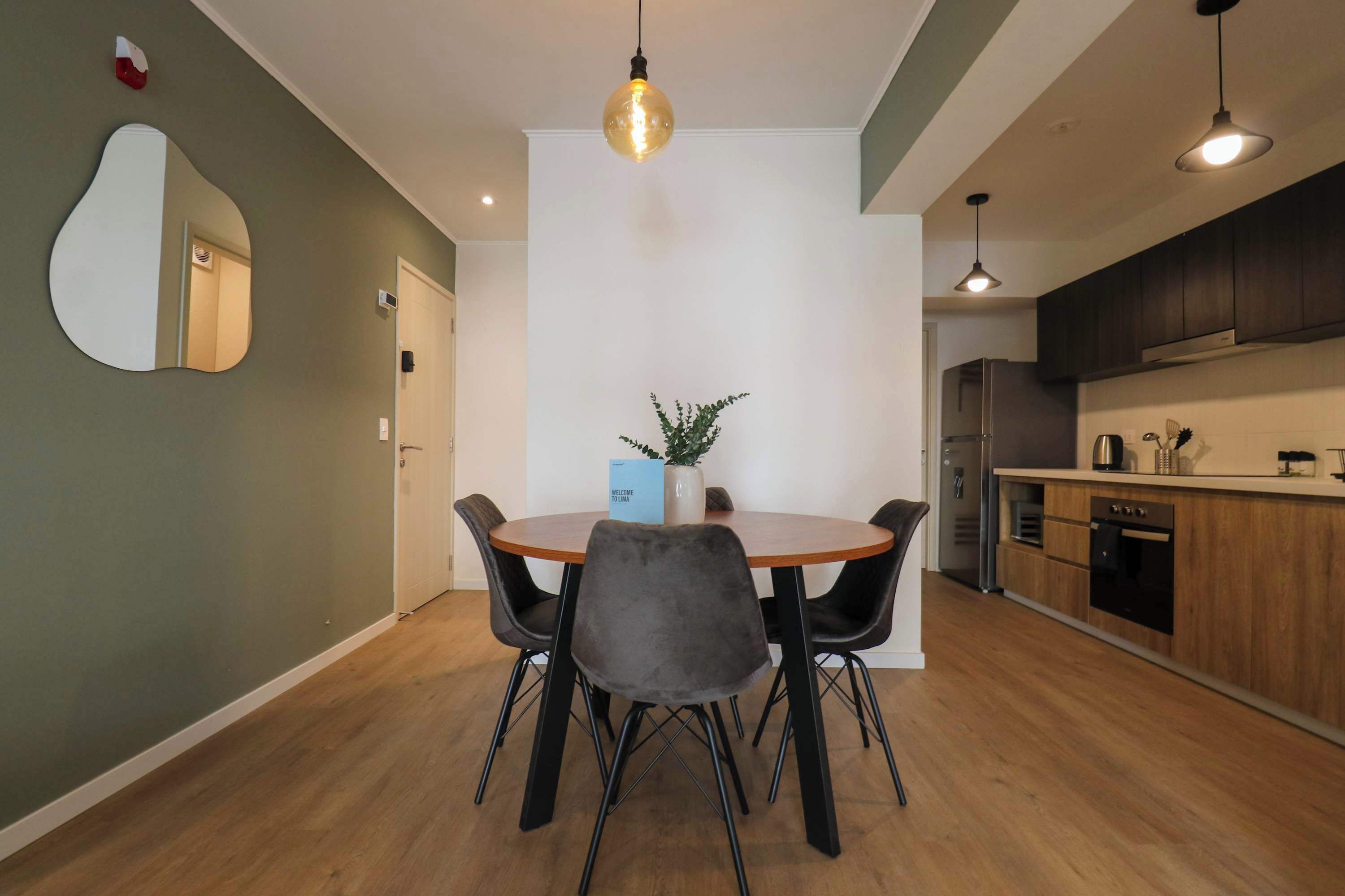Een moderne keuken met donkere houten kastjes, een inbouwoven en een roestvrijstalen koelkast.