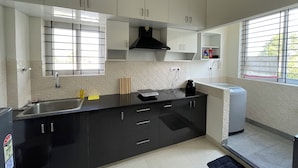 A modern kitchen with black cabinets, a stainless steel sink, and a window with blinds.