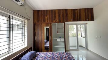 A bedroom with a bed, a wardrobe, and a sliding glass door.